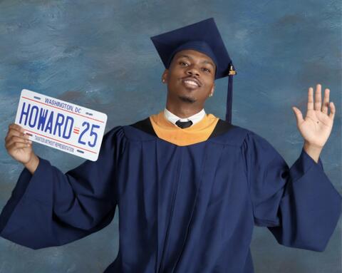 Eric posing in cap and gown with Howard 25 plates
